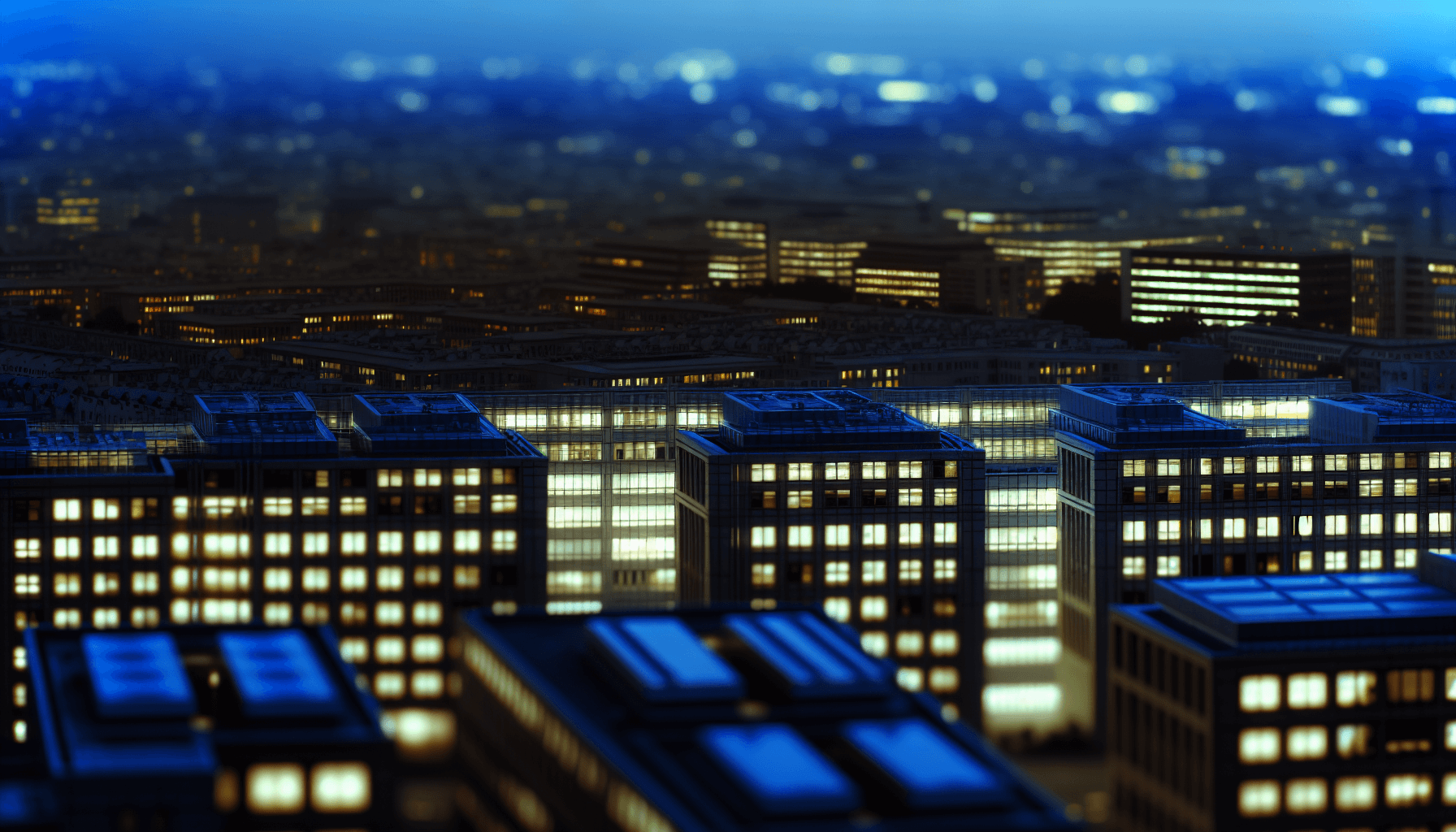 A cityscape at dusk with illuminated office buildings symbolizing technological interconnectedness.